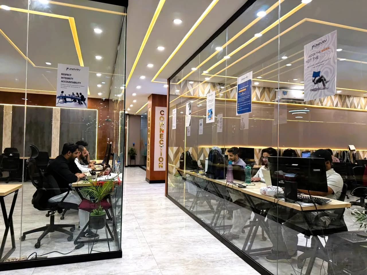 The open-plan office floor seen through glass partitions, with the team at their desks