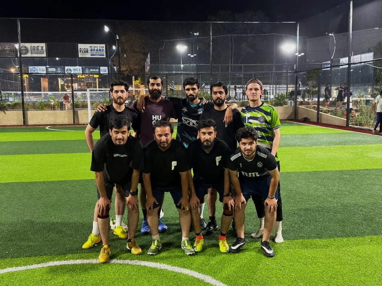 The team's football side posing on a floodlit pitch at night on sports day