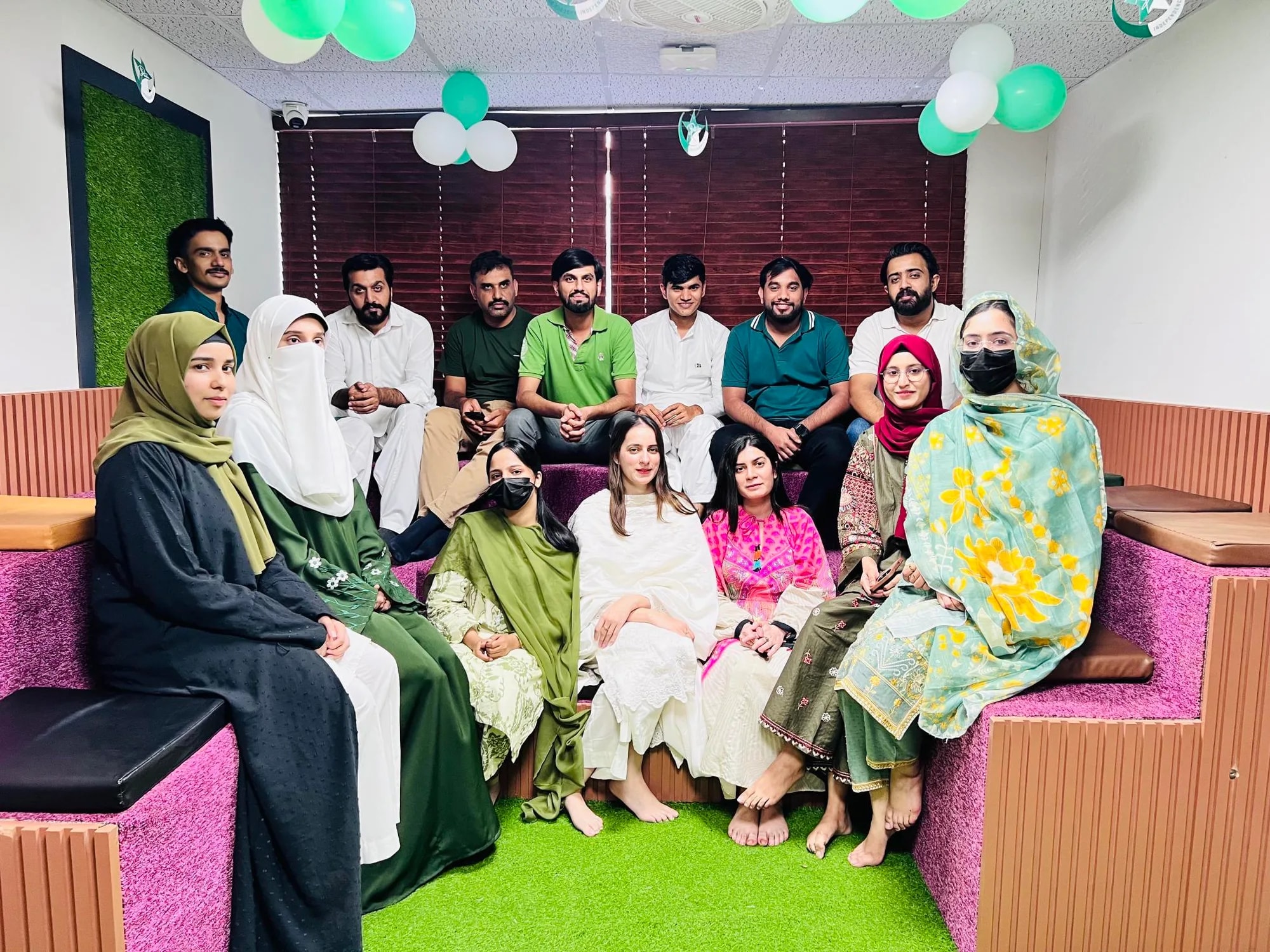The team dressed in green and white for Independence Day, gathered under green and white balloons at the office